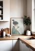 Modern kitchen decor featuring Japanese geisha wall art in a green kimono, sipping tea on a countertop with utensils and oranges