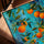 Contemporary oranges and foliage canvas with turquoise blue, styled with warm oak frame on table