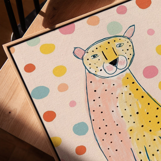 Cuadro infantil de leopardo rosa y amarillo con manchas - decoración mural con marco de roble dorado sobre mesa