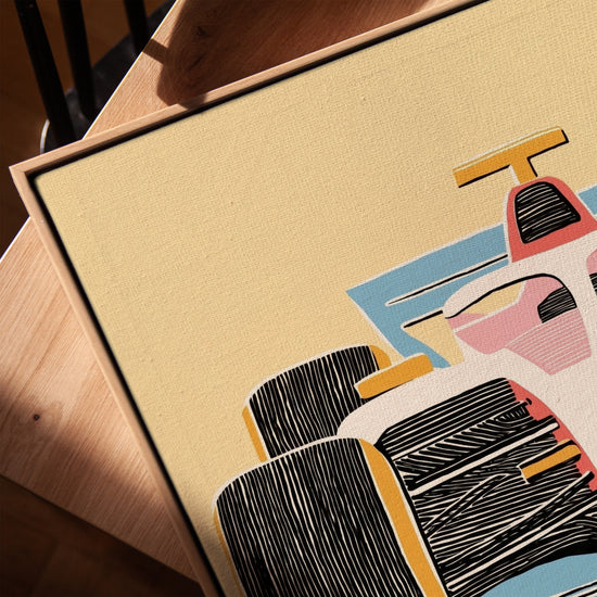 Tableau enfant voiture F1 rose corail et bleu sur toile avec cadre chêne doré posé sur table