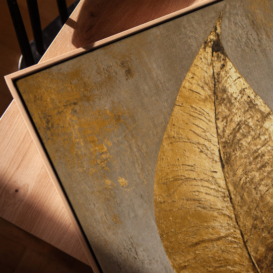 Goldenes Blatt auf grauem, texturiertem Grund auf Beistelltisch, stilvolle botanische Wanddekoration