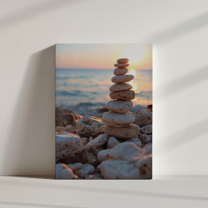Empilement de galets ovales clairs en équilibre sur une plage rocheuse au coucher du soleil, devant une mer calme aux reflets dorés.