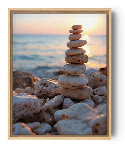 Stack of light oval pebbles balanced on a rocky beach at sunset, with a calm sea reflecting golden light