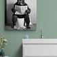 Tableau noir et blanc singe au toilette, installé au-dessus d'un évier dans une salle d'eau, captivant l'attention.
