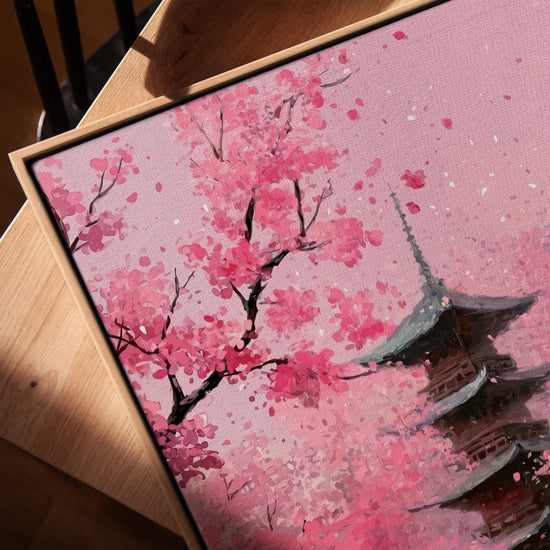 Tableau japonais pagode et cerisiers roses sur toile avec cadre chêne doré posé sur table salon