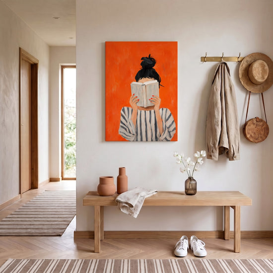 Tableau moderne femme lisant sur fond orange vif accroché dans une entrée contemporaine élégante