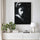 Tableau portrait noir et blanc représentant une geisha au regard baissé, accroché sur toile texturée dans un salon minimaliste lumineux avec meuble blanc, plante verte et décoration épurée