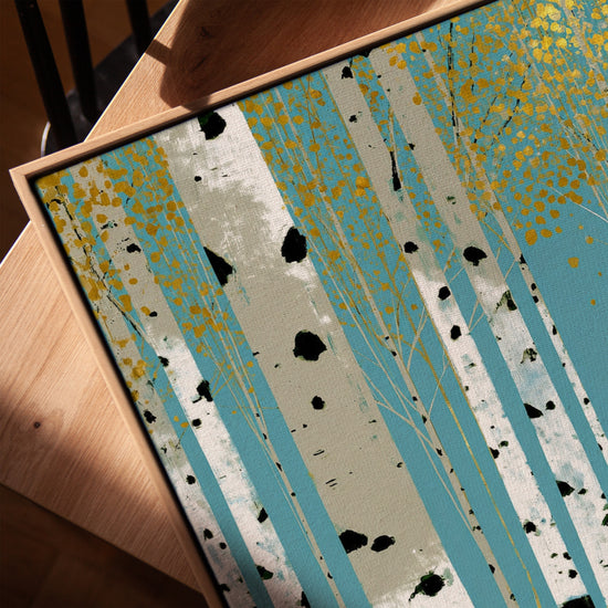 Birch forest canvas print with white trunks and golden leaves on blue background in a modern living room, framed in golden oak