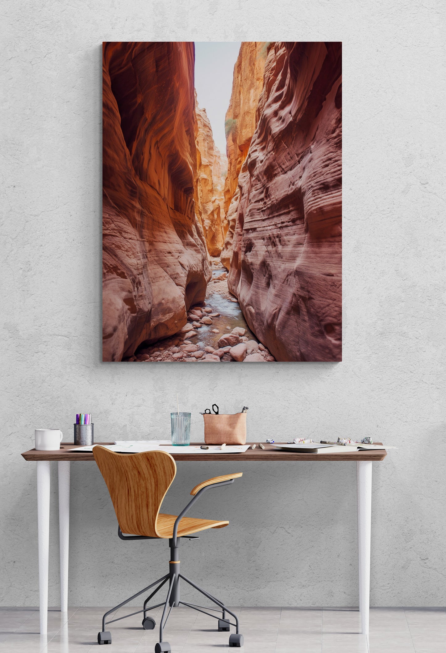 un magnifique paysage de canyon est accroché au mur au-dessus d'un bureau moderne. Le bureau est orné de divers accessoires, notamment une tasse, des stylos et une paire de lunettes. Une chaise en bois au design élégant est placée devant le bureau.