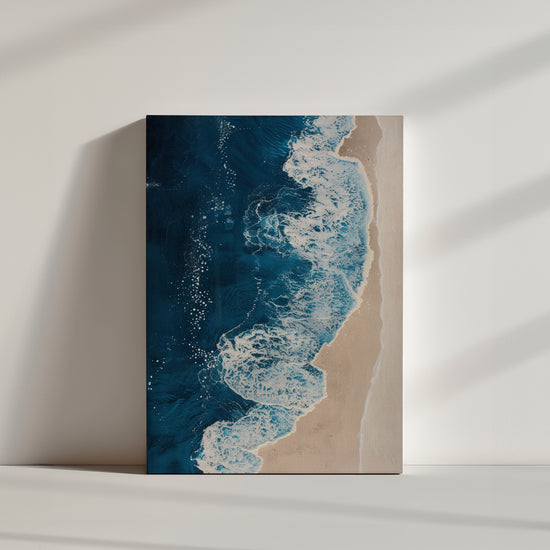 Un tableau représentant une plage vue d'en haut, avec des vagues bleues profondes s'écrasant sur le sable beige.