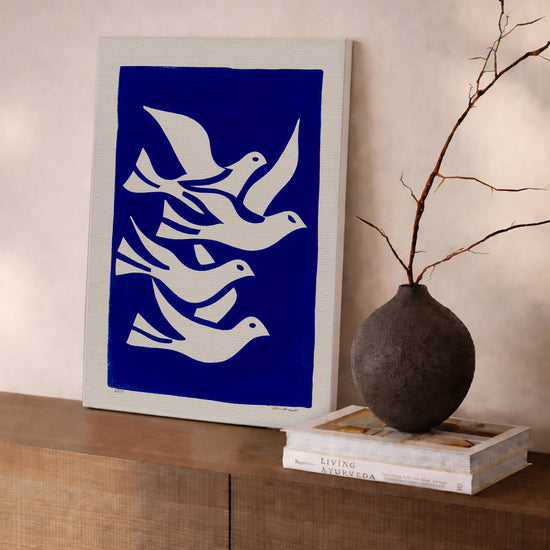 Blue and white dove canvas wall art hanging above a modern sideboard