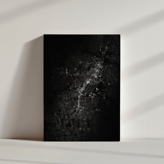 Monochrome night aerial cityscape with glowing roadways weaving through a dense urban fabric
