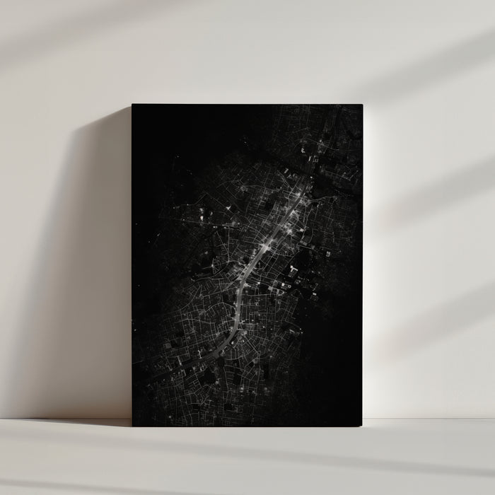 Monochrome night aerial cityscape with glowing roadways weaving through a dense urban fabric
