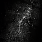 L'image en noir et blanc montre une vue aérienne nocturne de routes illuminées serpentant à travers le dense tissu urbain d'une ville