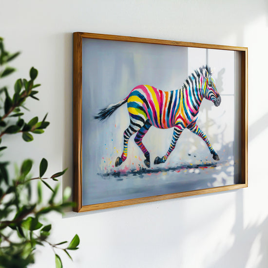 Affiche encadrée représentant un zèbre aux rayures arc-en-ciel, accrochée sur un mur blanc et entourée de feuillage.
