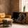 Zebra portrait in black and white with gold stripes, wall art in a living room with brick wall and leather armchair