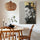 Decorative canvas art of a female portrait in black, gray and gold accents; textured canvas print styled in a warm dining room with wood table, rattan chairs and natural pendant light; modern contemporary wall decor
