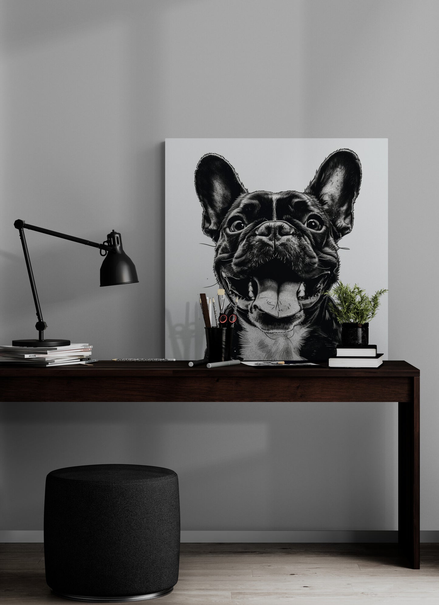 bureau en bois foncé, pouf noir, lampe noire, pile de livres, pot à crayon, plante, poster chien portrait.