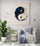 Artistic print of a navy blue and white textured yin yang with gold accents, displayed on the wall of a minimalist living room.