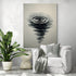 Grande toile en noir et blanc représentant une goutte d’eau et ses cercles concentriques en style encre de Chine, accrochée dans un salon moderne avec fauteuil blanc, plaid gris, coussin décoratif et plante verte tropicale