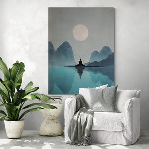 Grande toile zen représentant un Bouddha méditant devant un lac et des montagnes bleues sous une pleine lune, accrochée dans un coin lecture avec fauteuil blanc, plaid, coussin décoratif, plante verte tropicale et table basse design
