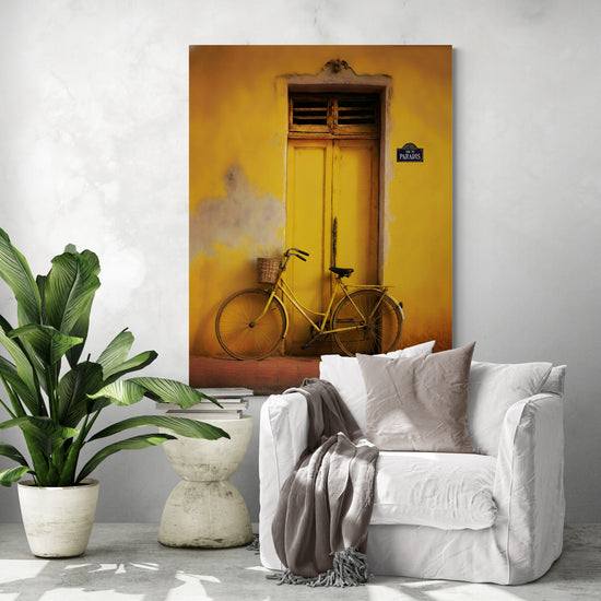 Vintage yellow bicycle artwork on a yellow wall above a white chair in a modern living room.