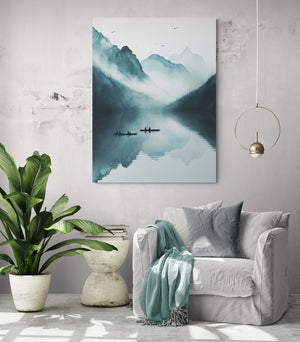 Un fauteuil large en lin gris clair avec coussins et plaid vert d’eau est placé sous une grande toile représentant des montagnes brumeuses. Une lampe suspendue dorée et une plante verte accentuent l’ambiance naturelle et relaxante d’un coin lecture cosy.