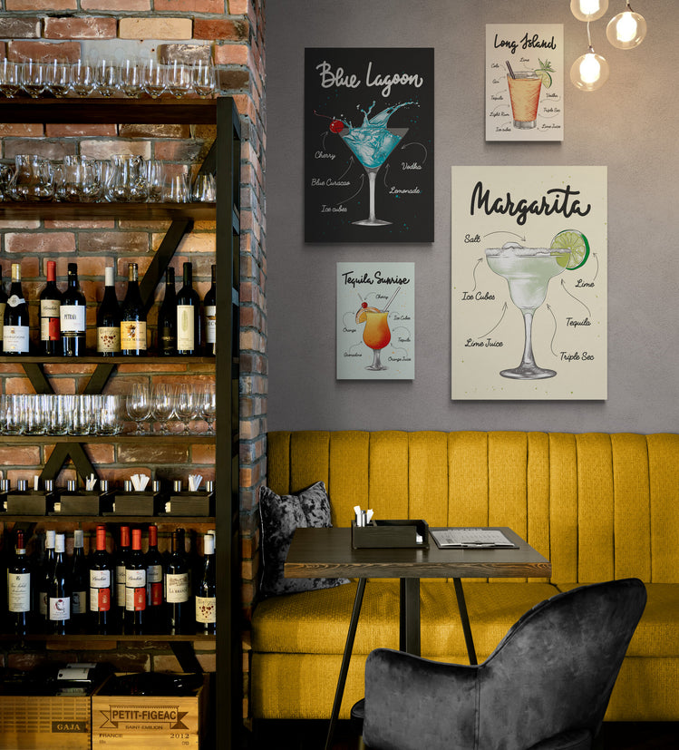 Un restaurant avec sur la droite une étagère pleine de bouteilles de vin et sur la gauche au-dessus d’une banquette en daim jaune, une décoration avec plusieurs tableaux de la même collection accroché au mur . Sur chaque toile un verre de cocktail différent et les ingrédients nécessaires à sa réalisation