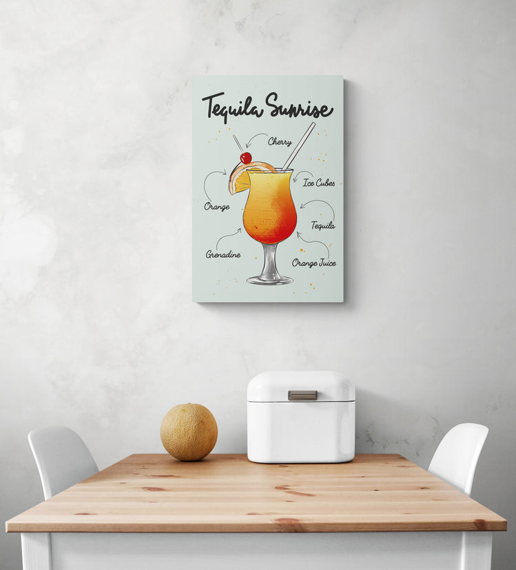 Il y a un petit tableau pour cuisine sur mur blanc. Le tableau déco montre un verre à cocktail de tequila Sunrise La décoration d'intérieur est minimaliste avec Deux chaises blanches à proximité d'une table à manger en bois. Une corbeille à pain en métal blanc et un melon sont posés sur la table.