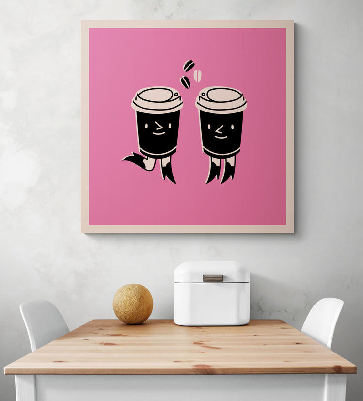 Un tableau déco rose est accroché sur le mur d'une cuisine blanche. Ce tableau cuisine est placé ce au-dessus d'une table en bois et deux chaises sont de chaque côté. Une boîte à pain en métal blanc et un melon sont sur la table