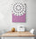 A dragon fruit artwork hangs on a white wall. The painting uses vibrant purples and whites that blend and contrast harmoniously. Below the artwork is a wooden table with two white chairs, creating a comfortable space. On the table sits a white metal bread basket and a small green melon.