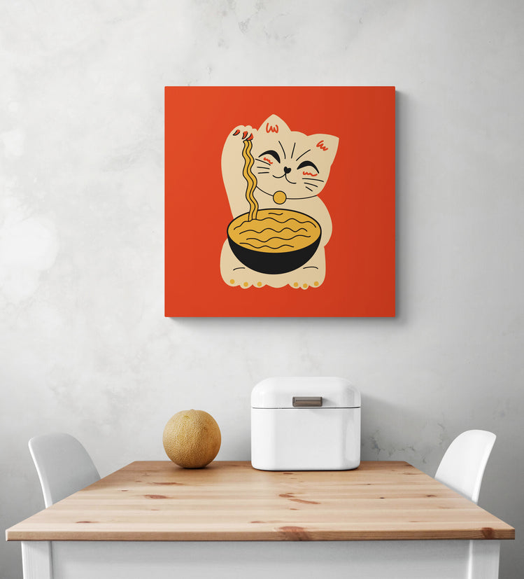 Un tableau orange avec un chat maneki-neko est disposé au centre de l'image. Dessous une table de repas blanc et en bois naturelle aux extrémités deux chaises blanche un melon et une boîte à pain sont sur la table.