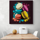 Un tableau cuisine macaron multicolore sur fond noir dans un style pop art des éclaboussures de peinture. Ce tableau cuisine est placé ce au-dessus d'une table en bois et deux chaises sont de chaque côté.