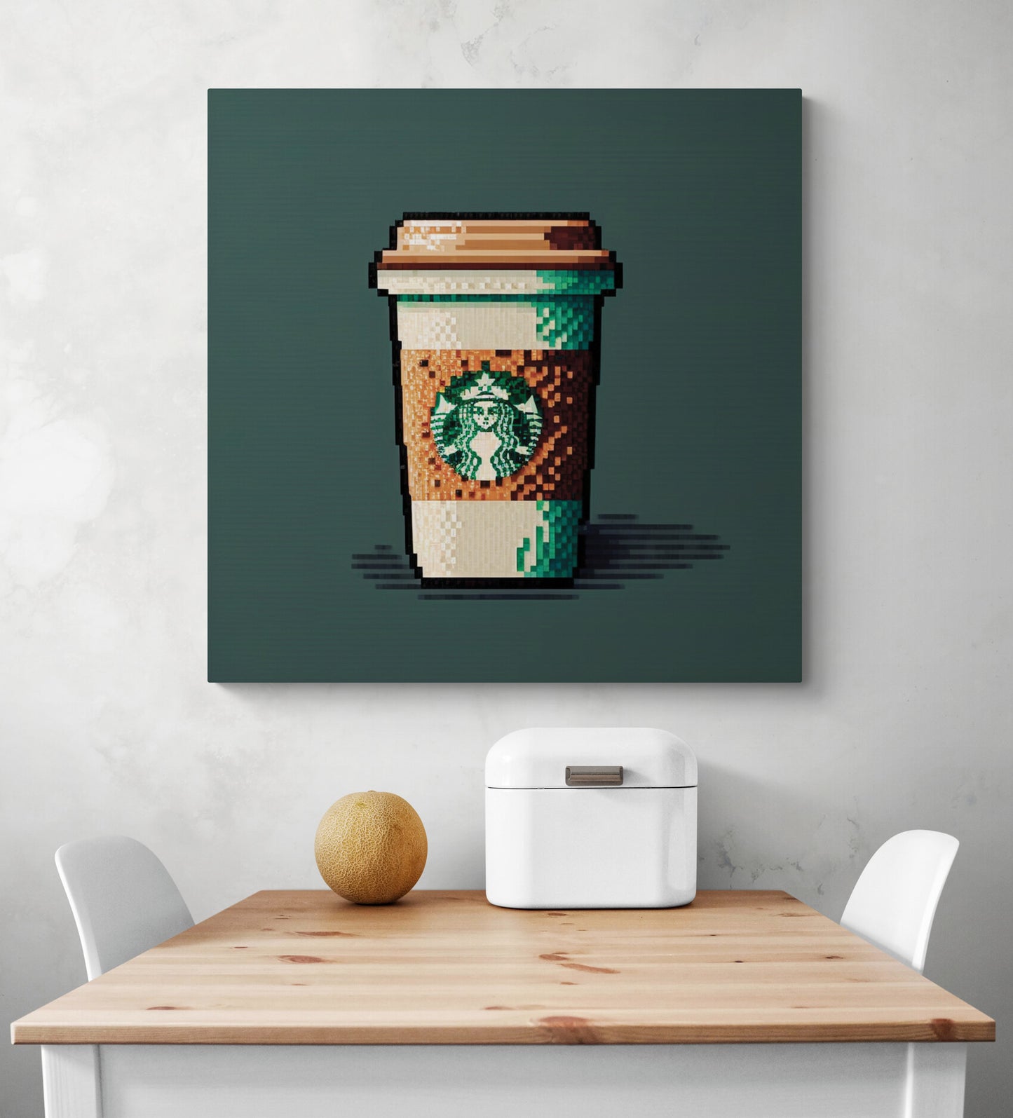 Une tasse de café Starbucks en pixel art sur toile de coton de grande taille, dans une cuisine blanche et épuré, avec des couleurs marron et vert contrastantes pour une esthétique raffinée et confortable. L’impression rendu est cosi et chaleureuse