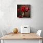 Un petit tableau deco pour cuisine avec des fleurs rouges est accroché sur un mur blanc au-dessus d'une table de cuisine en bois