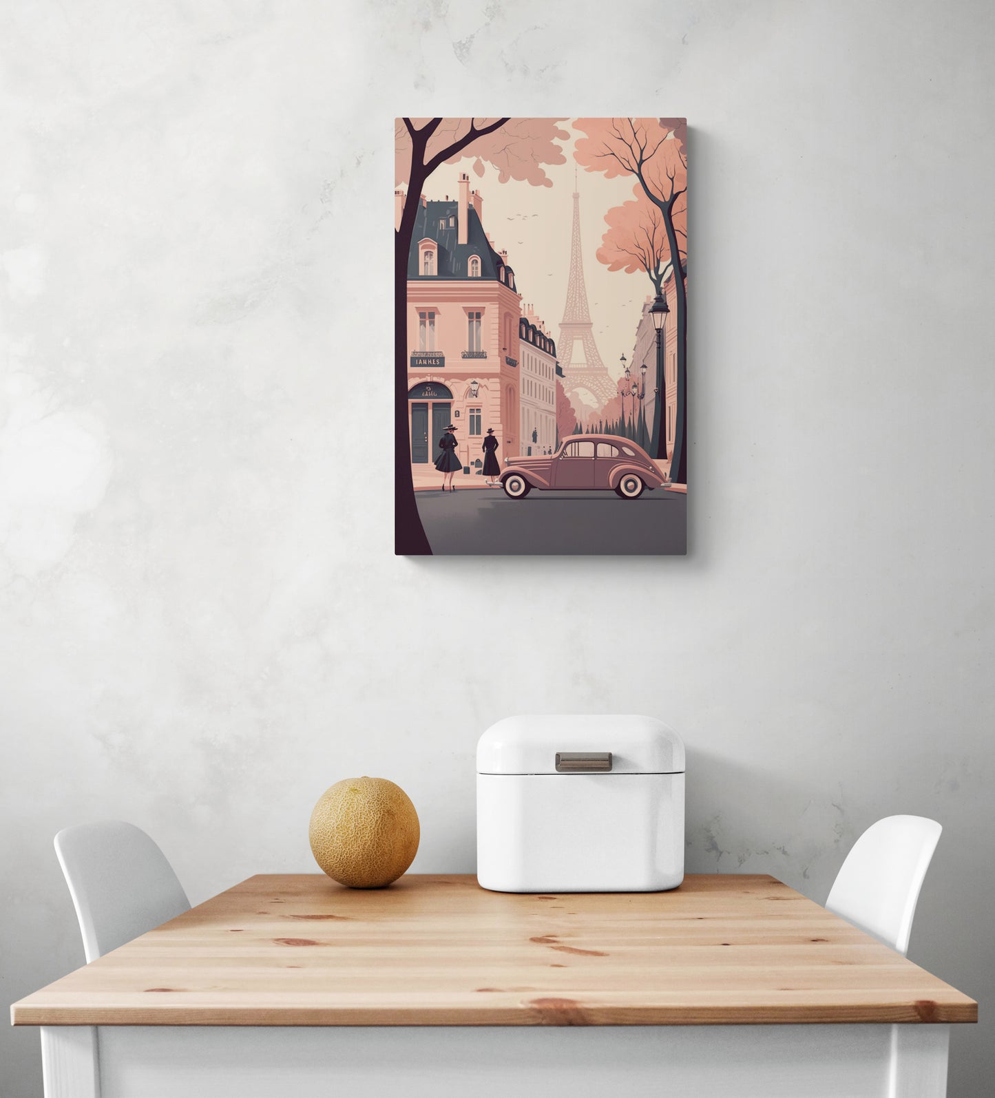 Tableau metal vintage dans un style rétro des années cinquante avec des couleurs pâles rose et gris est accroché au milieu d'un mur blanc. Sur ce tableau pour cuisine on peut apercevoir une ruelle et des bâtiments parisiens, en arrière-plan on aperçoit la tour Eiffel. Sur la photo il y a également une table et deux chaises blanches.