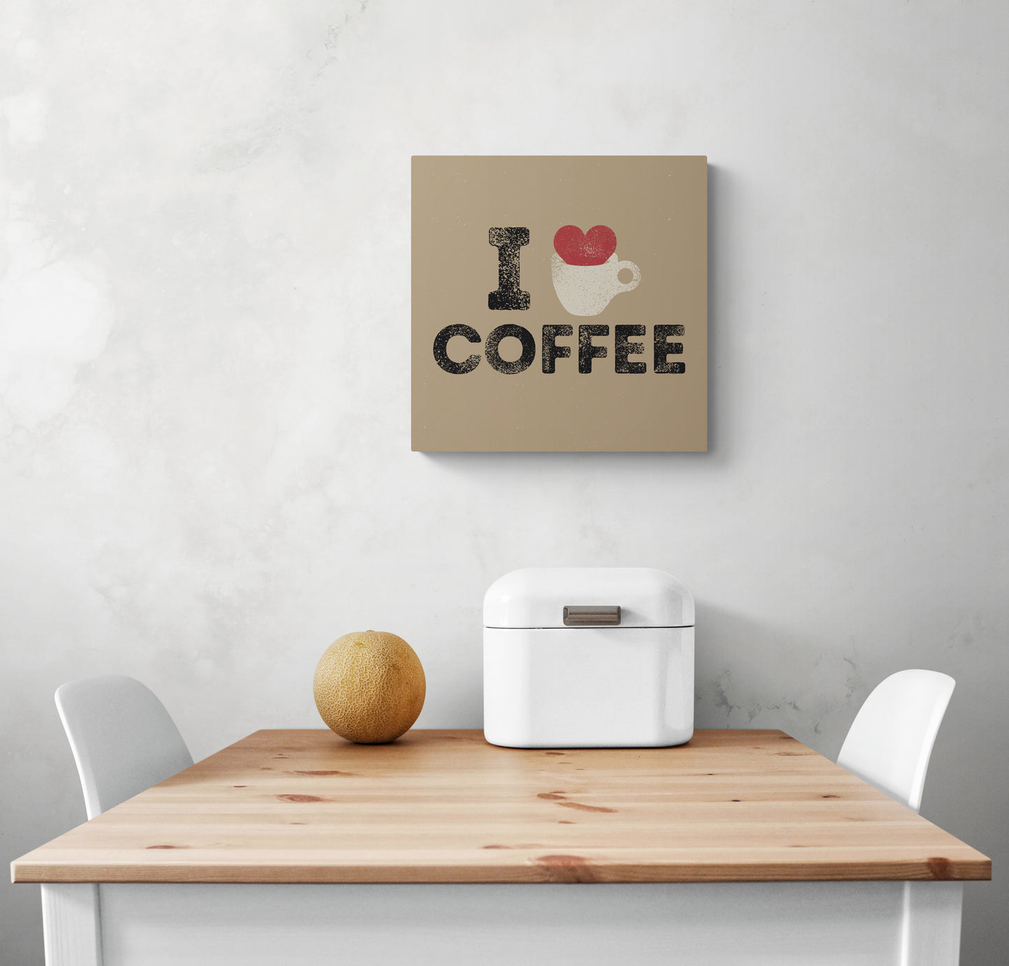 Tableau mural cuisine beige avec une illustration d'un cœur rouge qui déborde d'une tasse de café et une inscription en noir i love café, accroché sur un mur blanc