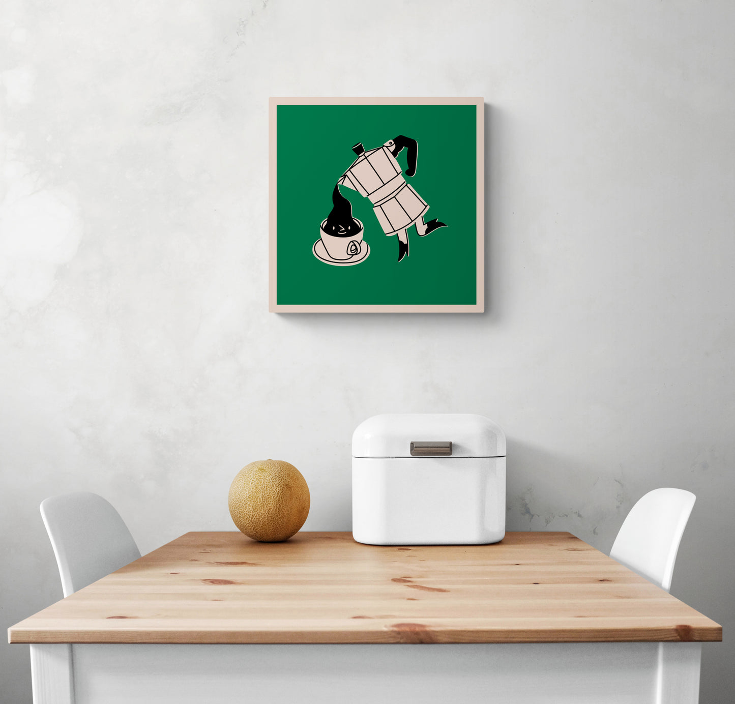 Un tableau de cuisine est accroché sur un mur blanc. Ce tableau est placé au-dessus d'une table en bois et deux chaises sont de chaque côté. Une boîte à pain en métal blanc et un melon sont sur la table