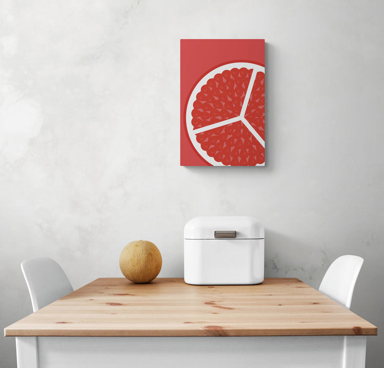 Un petit tableau deco pour cuisine est accroché sur le mur blanc d'une cuisine. Au centre de l'image se trouvent une table en bois et deux chaises blanches. Posé sur la table une corbeille à pain et un petit melon. Tous ces éléments créent un look coloré et harmonieux dans la pièce.