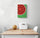 Small kitchen wall art on a white wall - vivid red and green fruit print above a white table and two chairs, white metal bread basket and a small melon - fresh, colorful dining decor