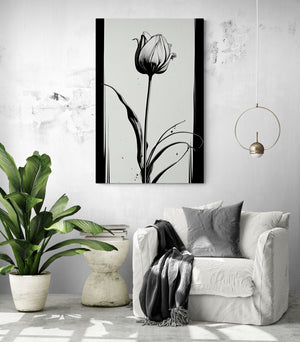 A crumpled white fabric armchair sits in a bright room. A black and gray throw is draped over the armrest, accompanied by a matching gray pillow. Next to it, a sculpted stone side table holds a stack of books. A large potted green plant adds a natural touch. On the white textured wall, a black and white painting of a stylized tulip draws attention. A minimalist gold pendant light with a thin circle and a hanging bulb.