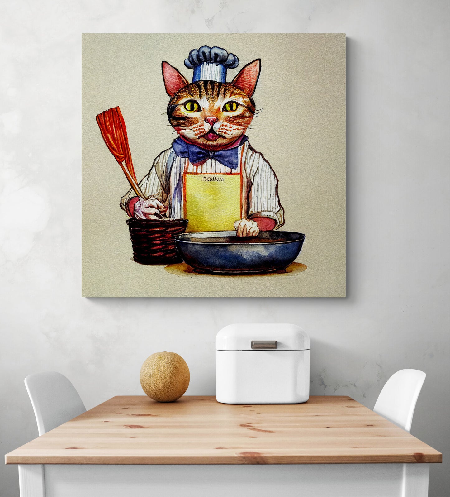 Accrochée sur le mur d'une cuisine, au-dessus d'une table en bois une toile en polyester est accrochée sur le mur, il y a une illustration d'un chat qui se tient de face prêt à cuisiner. L'objet de décoration est plutôt original et le chat mignon il porte une tenue de cuisinier avec une toque, il tient dans ça main une spatule. Une corbeille à pain en métal blanc et un melon sont posés sur le dessus d'une table en bois.