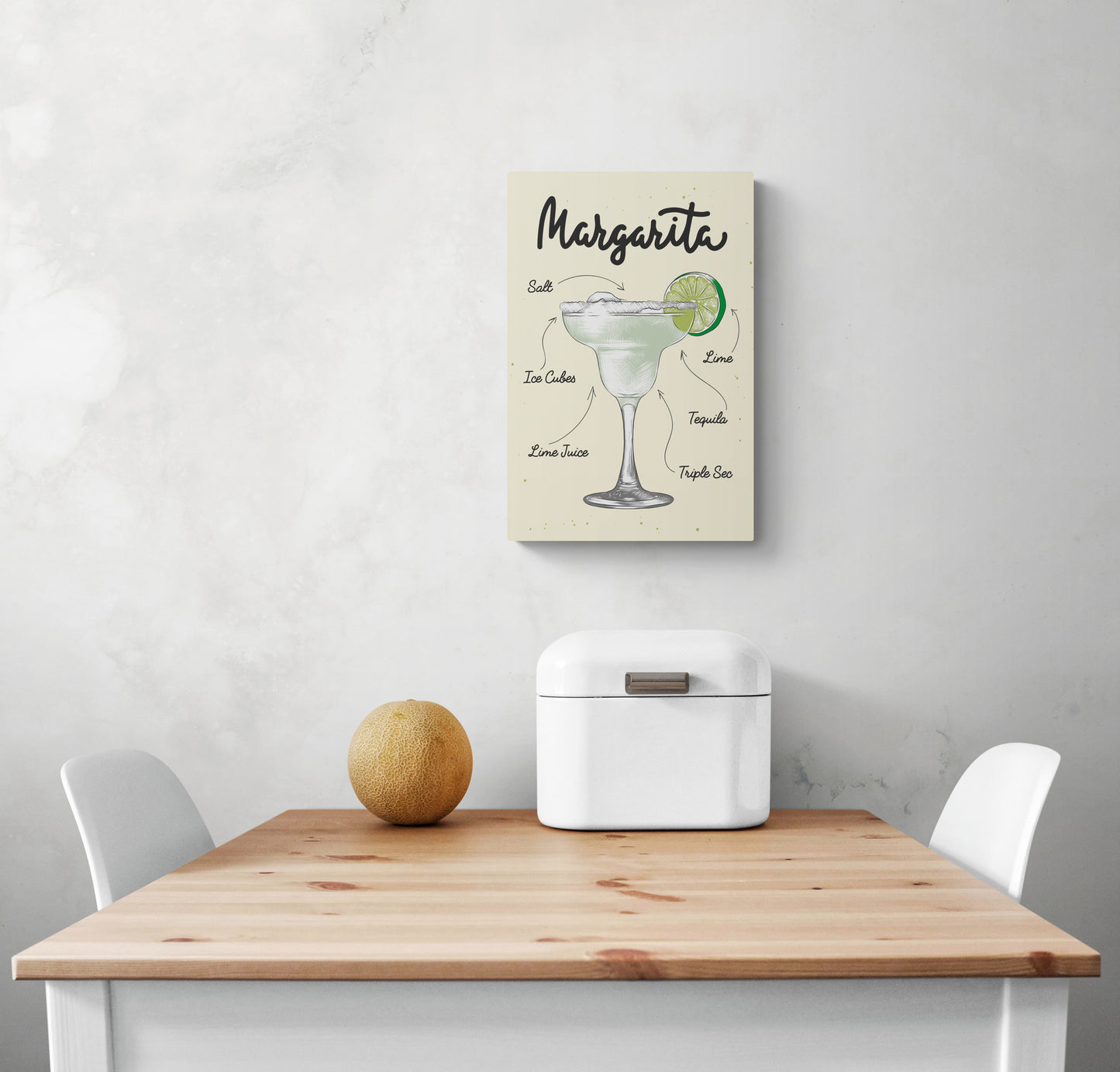 une deco cadre cuisine avec un dessin de cocktail Margarita est placée sur un mur blanc avec des nuances de gris. La décoration murale est élégante et sobre. Une table à manger en bois et deux chaises blanches se trouvent dans la cuisine.